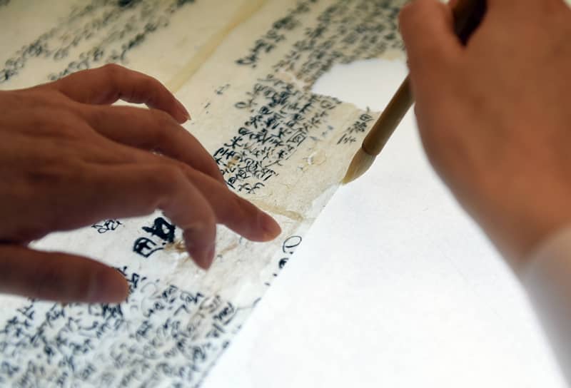 2022年5月17日，在安徽博物院文物科技保護中心紙質(zhì)文物修復室，工作人員對古籍文物進行補全。